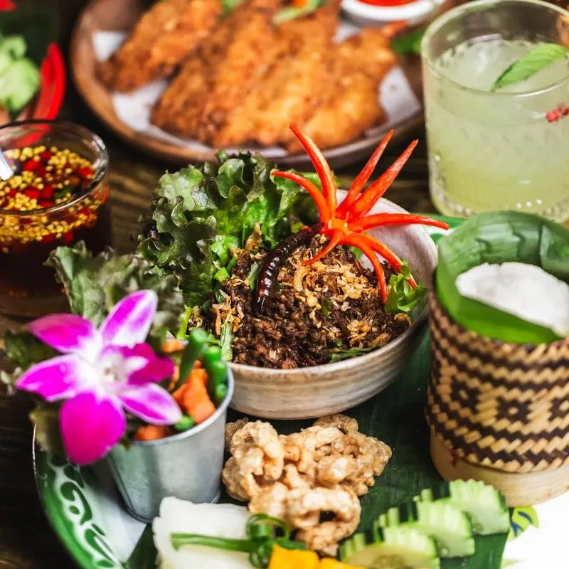 A table filled with bowls of Thai cuisine, drinks, and snacks.