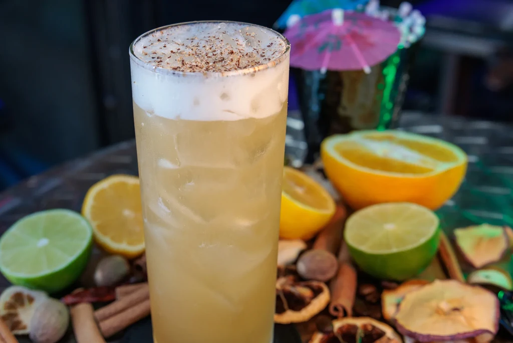 A tall, frosted cocktail with a foamy top and grated nutmeg.