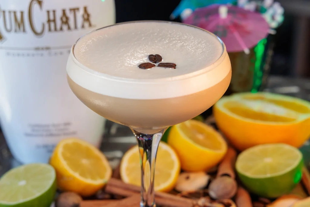 A creamy cocktail in a martini glass topped with three coffee beans.