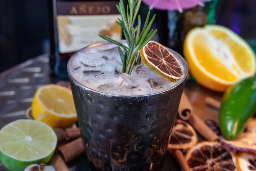A hammered metal cocktail glass with ice, rosemary, and dried citrus.