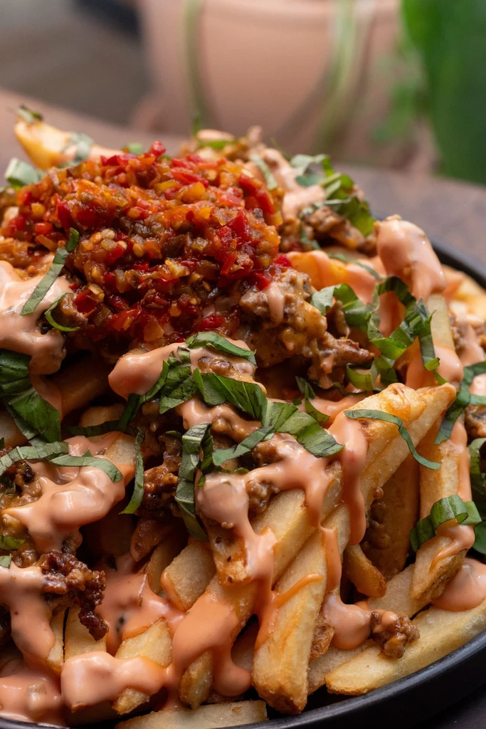 French fries topped with ground meat, sauce, chili relish, and basil.