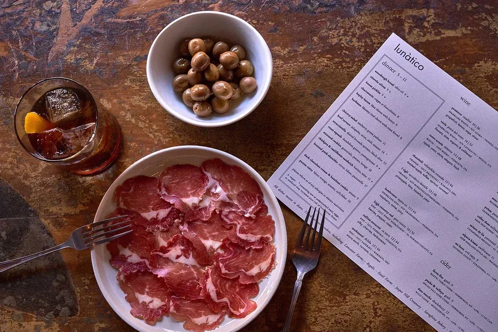 Overhead view of a dining table with food, drinks, and a menu.