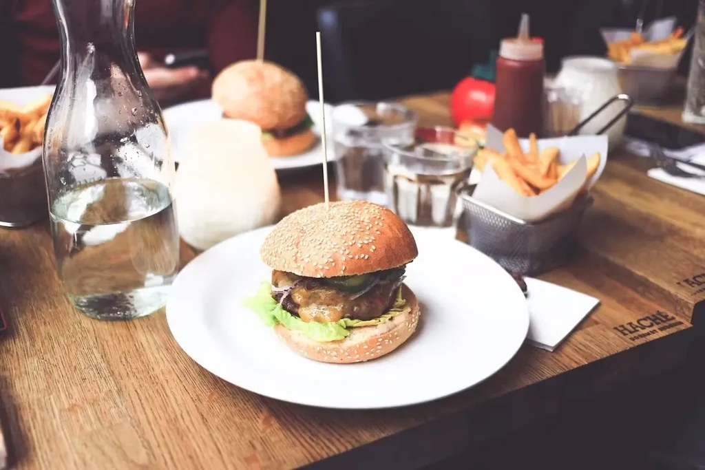 A table setting with two burgers, fries, and a water carafe.