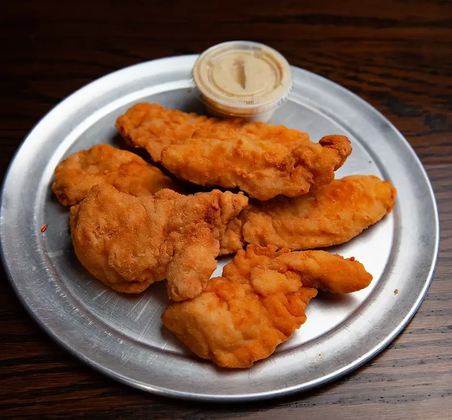 Fried chicken tenders and dipping sauce on a metal plate.