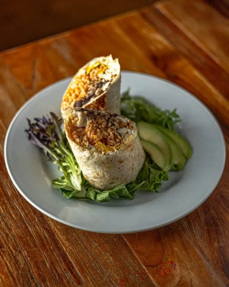 Two halves of a burrito with rice, beans, and avocado slices.