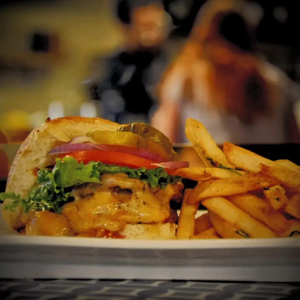 Close-up of a cheeseburger and french fries on a white plate.