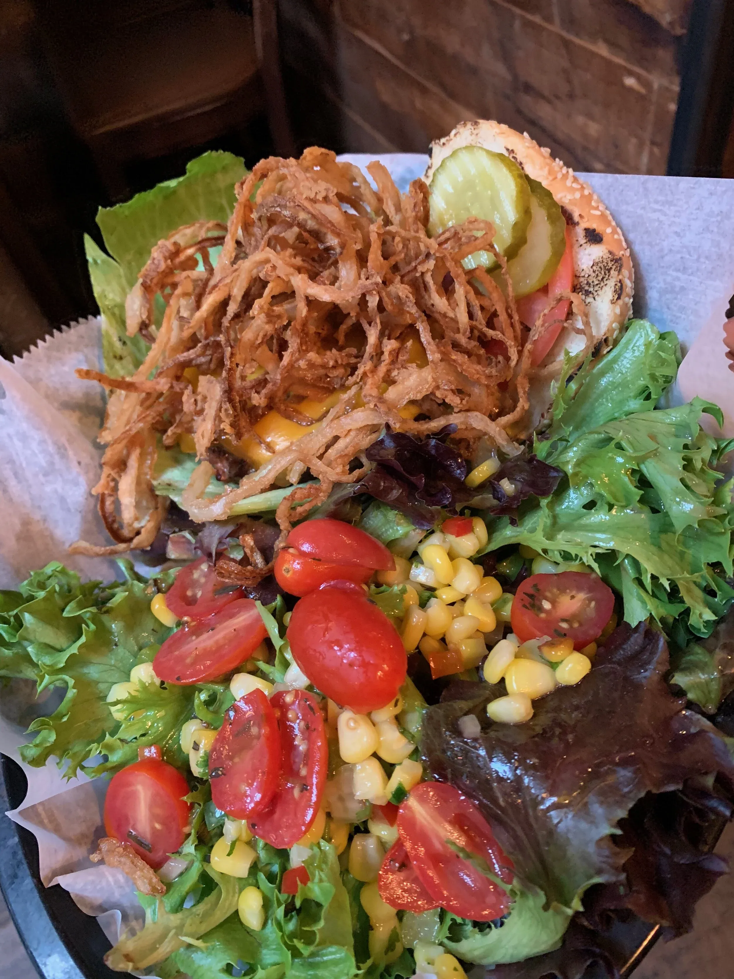 Cheeseburger with fried onions, pickles, and a side salad.
