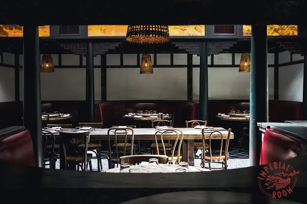 Interior view of a dim restaurant with booths, tables, and wicker lamps.