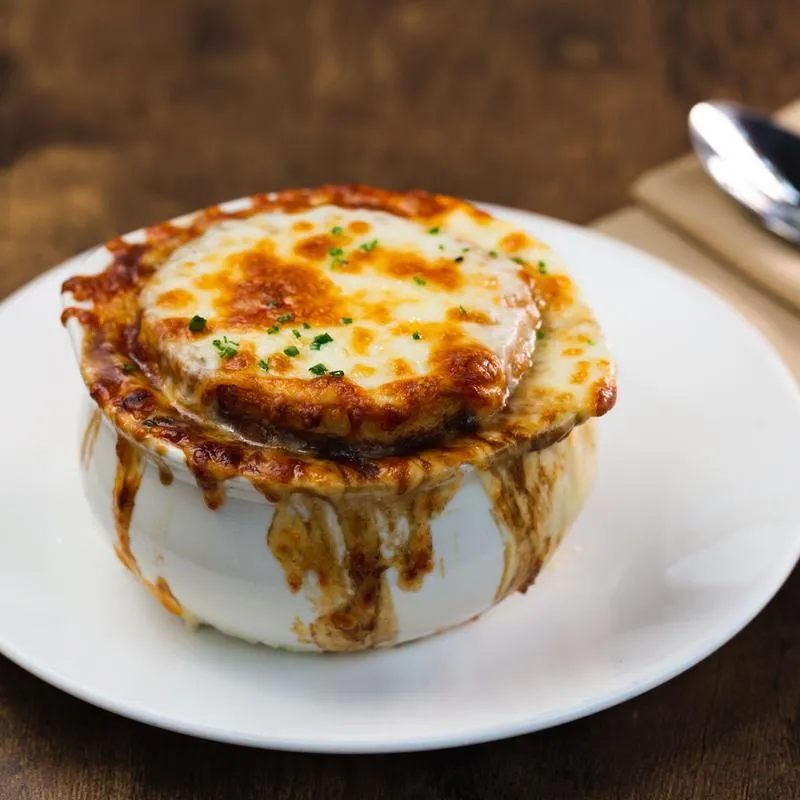 A bubbling bowl of French onion soup, topped with melted cheese.