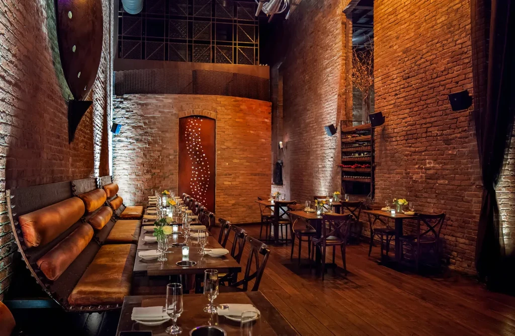 An upscale restaurant with brick walls, exposed metal, and wood tables.