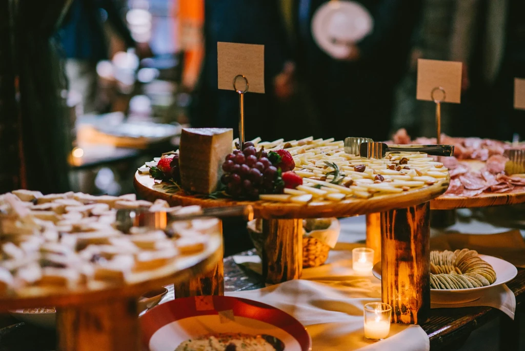 Cheese and charcuterie boards on elevated wooden platters with candles.
