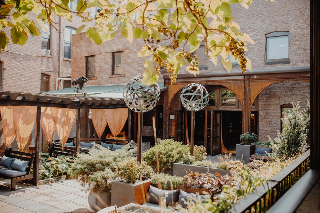 A leafy outdoor patio with brick buildings and abstract sphere sculptures.