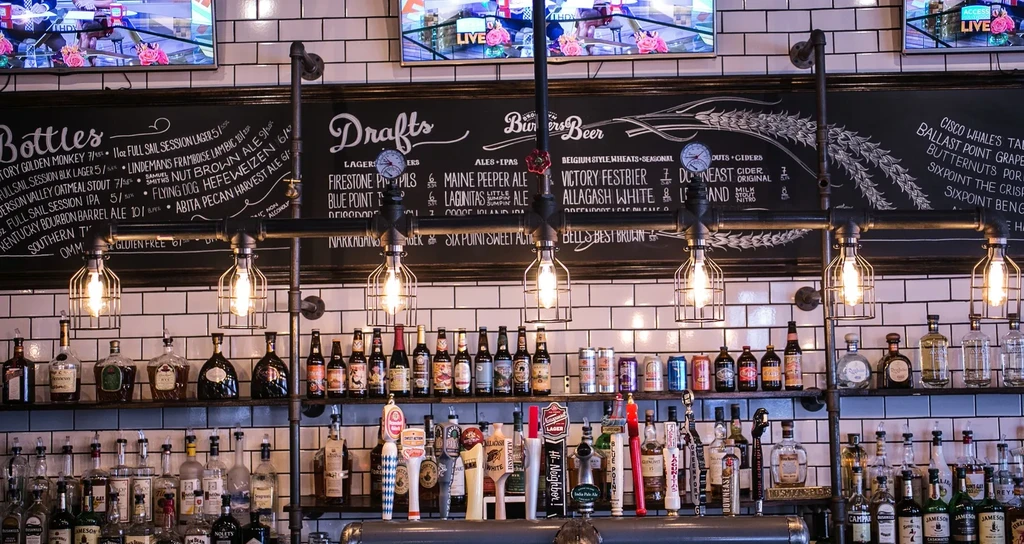 A black chalkboard with drink menus and bar shelves with liquor bottles.