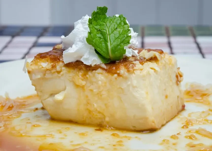A slice of flan topped with whipped cream and a mint leaf.