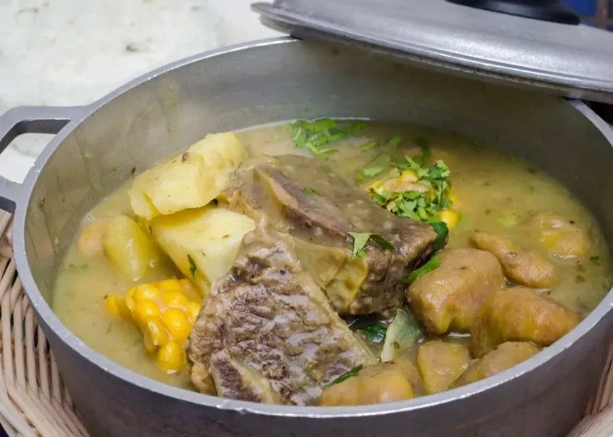 Sancocho in a pot, with potatoes, corn, meat, and plantain.