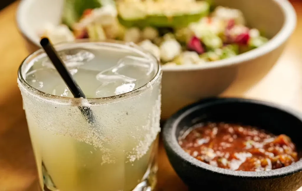 A margarita with a salted rim, salsa, and a salad.