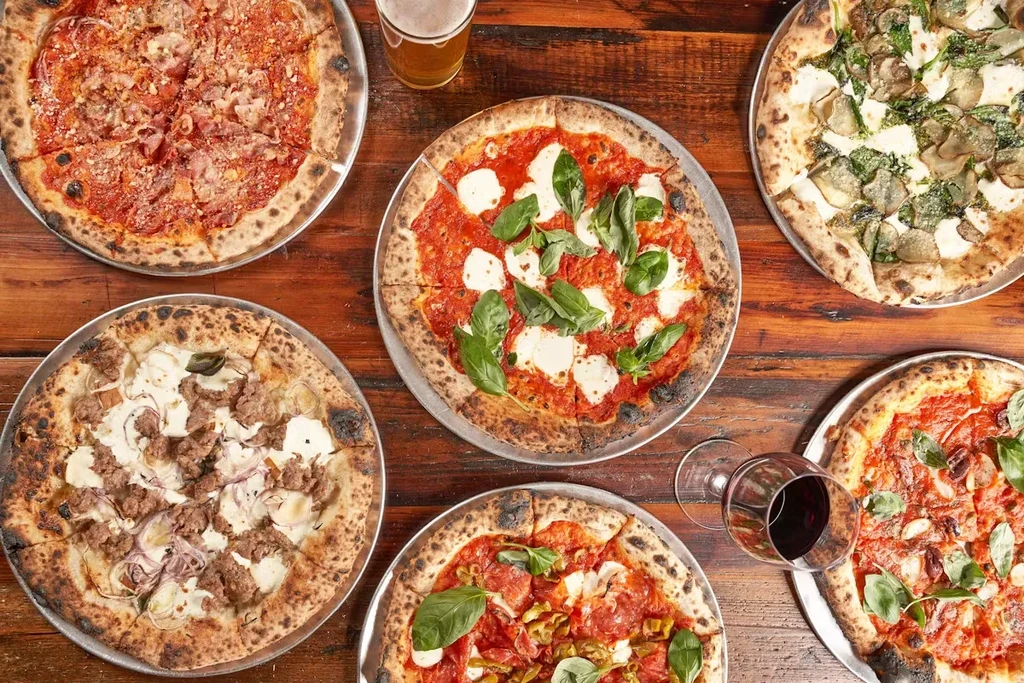 Six delicious pizzas with different toppings, a beer, and a glass of wine.