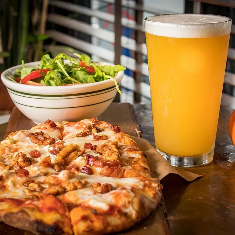 Pizza, salad, and beer on a wooden table.