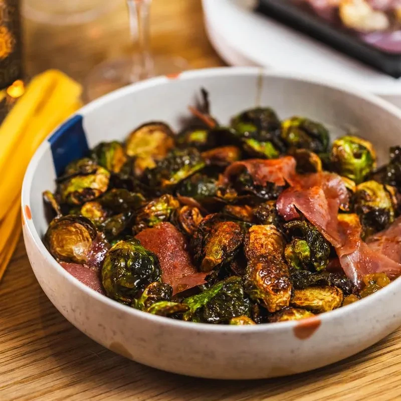 Roasted Brussels sprouts with prosciutto in a white bowl.