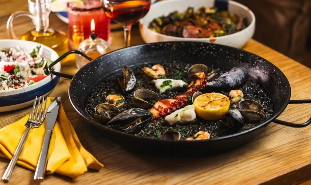 Black paella with octopus, mussels, clams, shrimp, and lemon.