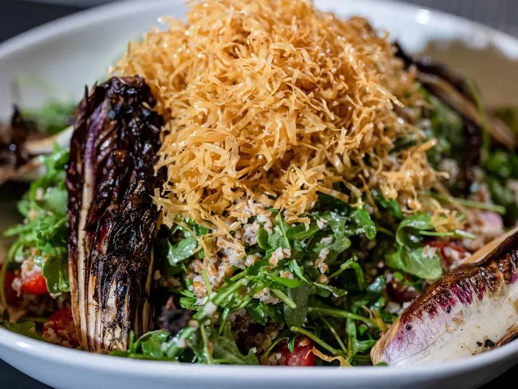 A bowl of salad with greens, grilled radicchio, and crispy fried onions.
