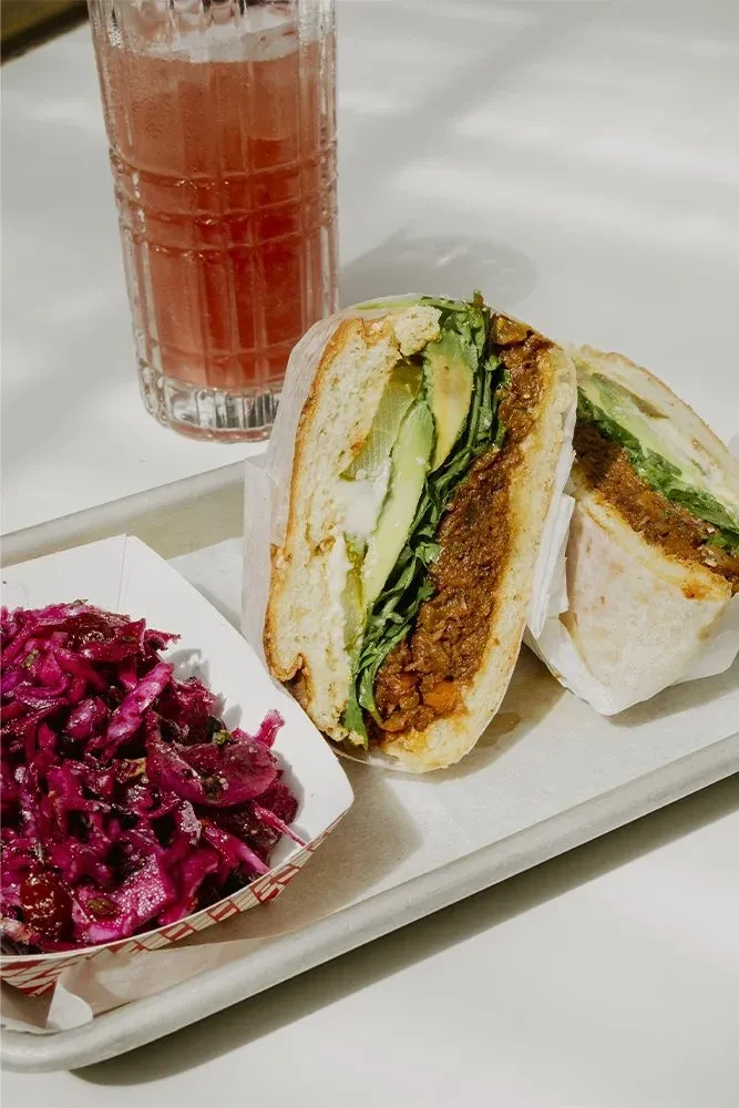 A sandwich, drink, and red cabbage salad on a white tray.
