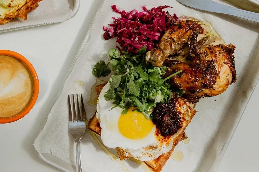 Chicken and waffles with a fried egg, red cabbage, and cilantro.