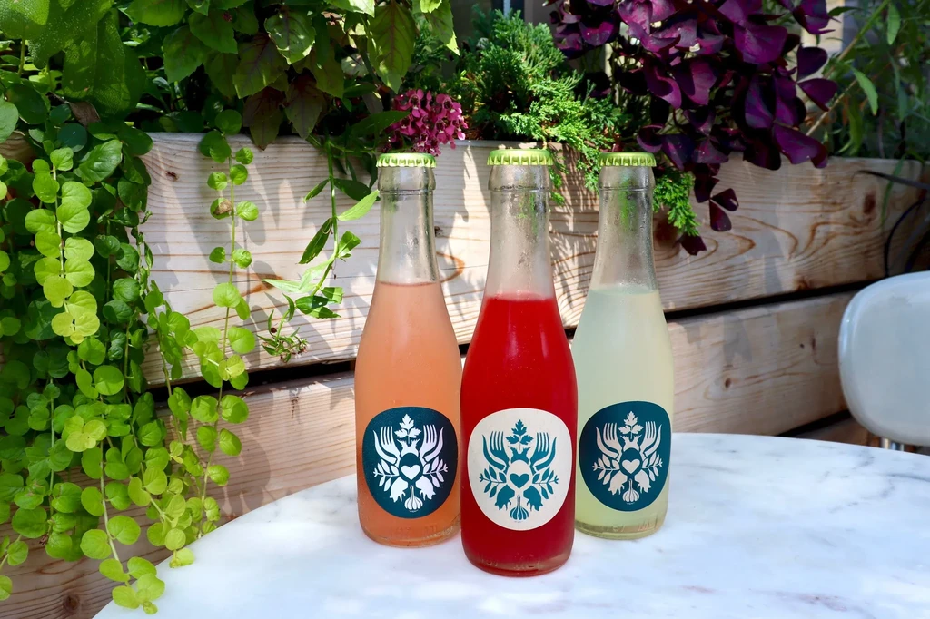Three colorful bottled drinks on a white marble table outdoors.