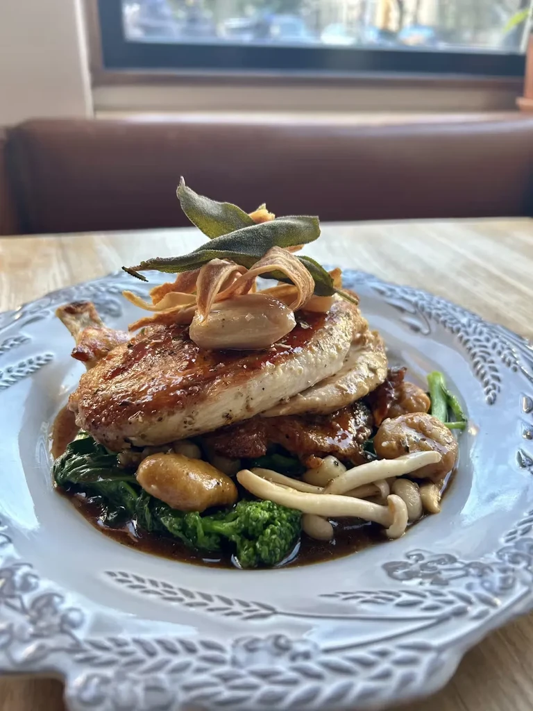A plate of chicken, spinach, broccoli, and mushrooms in sauce.