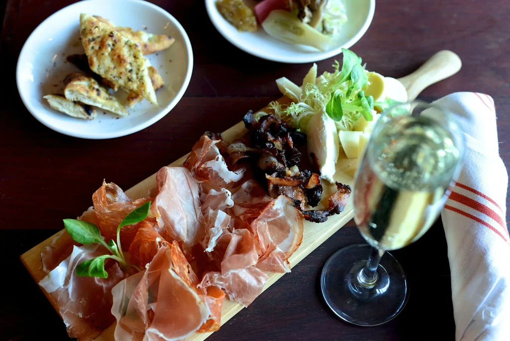 Charcuterie board with meats, cheese, focaccia, and a glass of champagne.