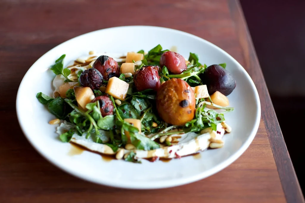 Arugula salad with grilled figs, melon, goat cheese, and pine nuts.