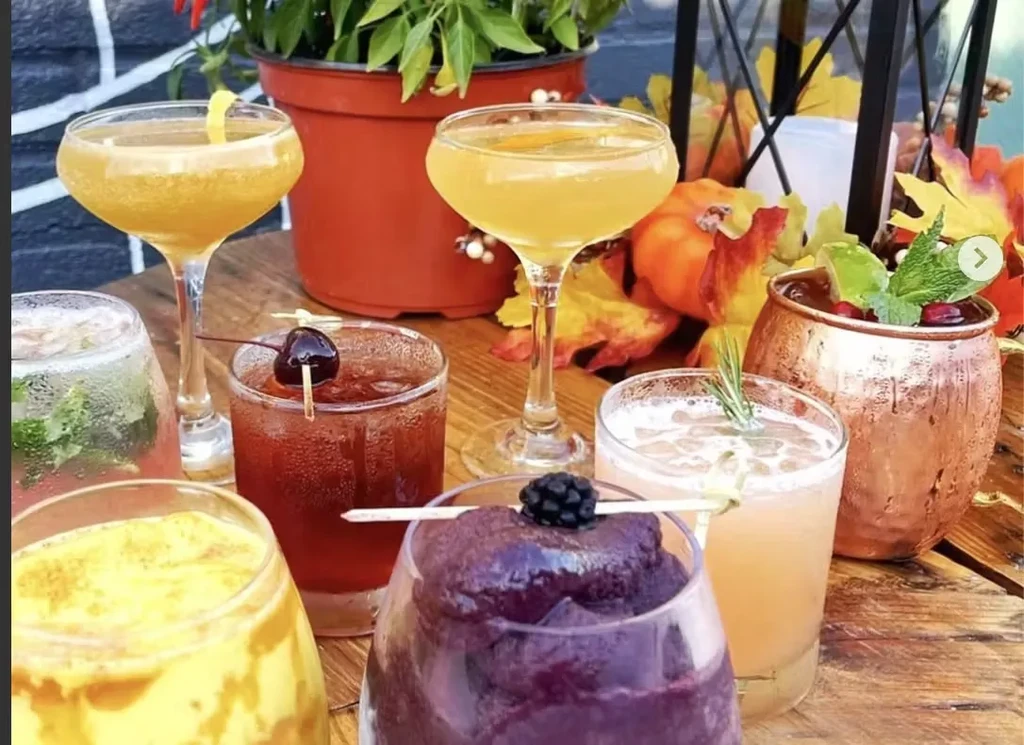 Variety of cocktails and drinks on a table with fall decorations.