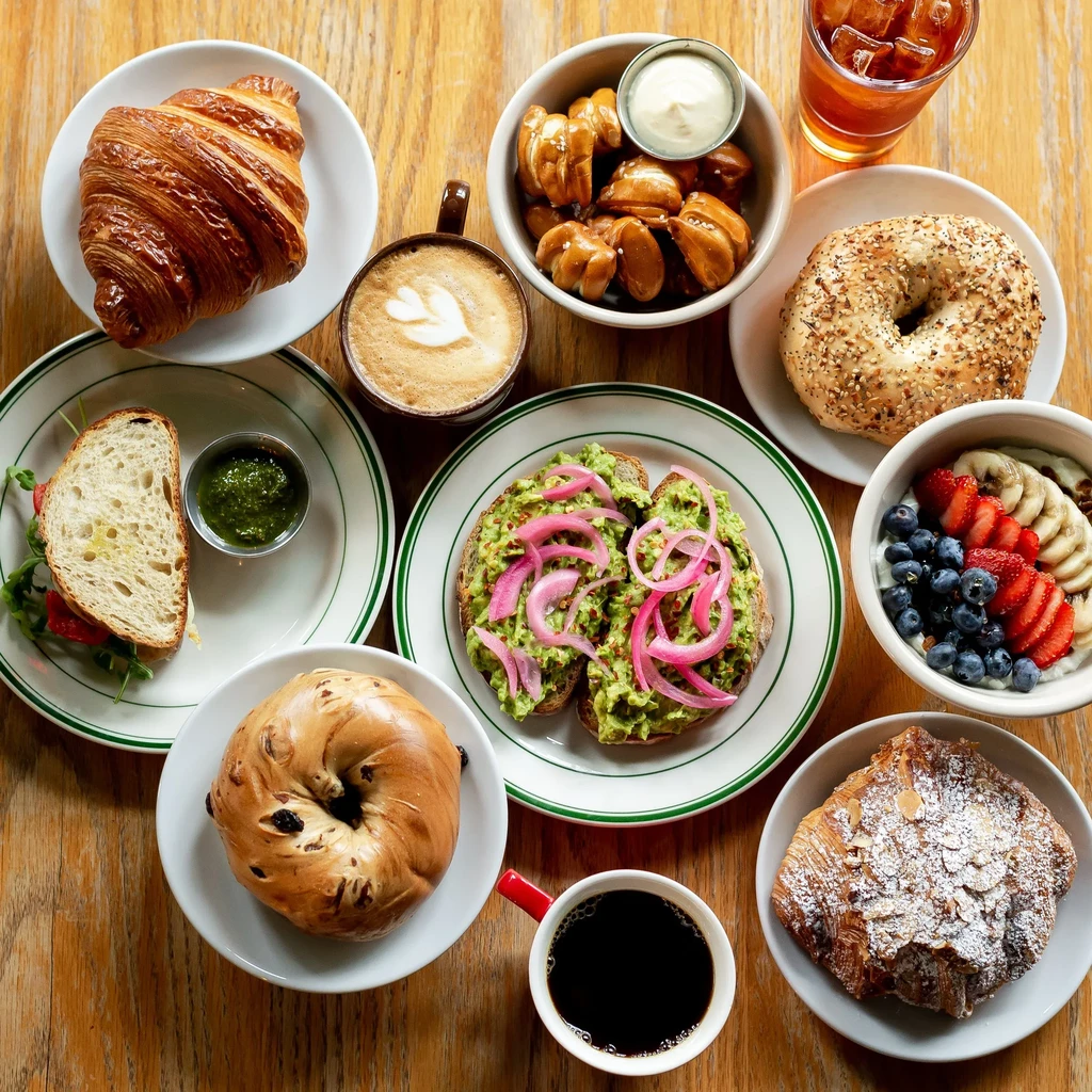 A table full of breakfast items, including avocado toast and croissants.