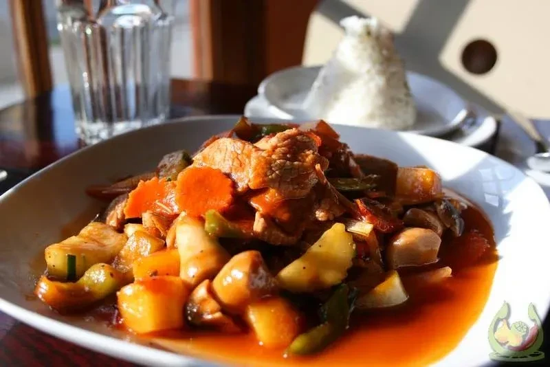 Plate of meat, carrots, and vegetables in orange sauce.