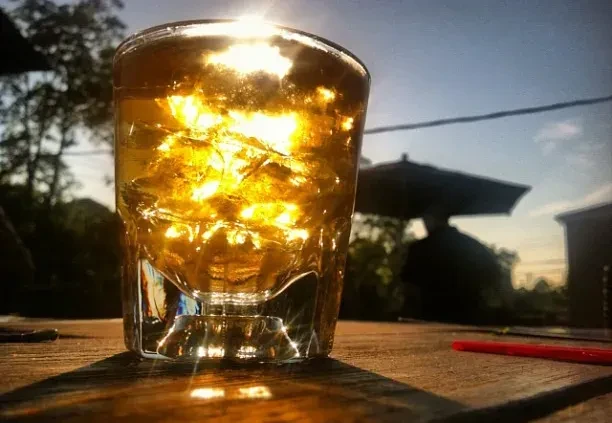 Iced drink sparkling on a wooden table in sunlight.