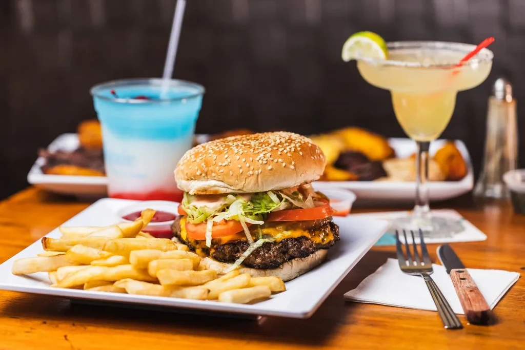 A cheeseburger and fries on a plate, with drinks nearby.
