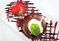 A chocolate cake with whipped cream, mint, strawberry, and berry drizzles.