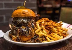 A cheeseburger with caramelized onions and a side of french fries.