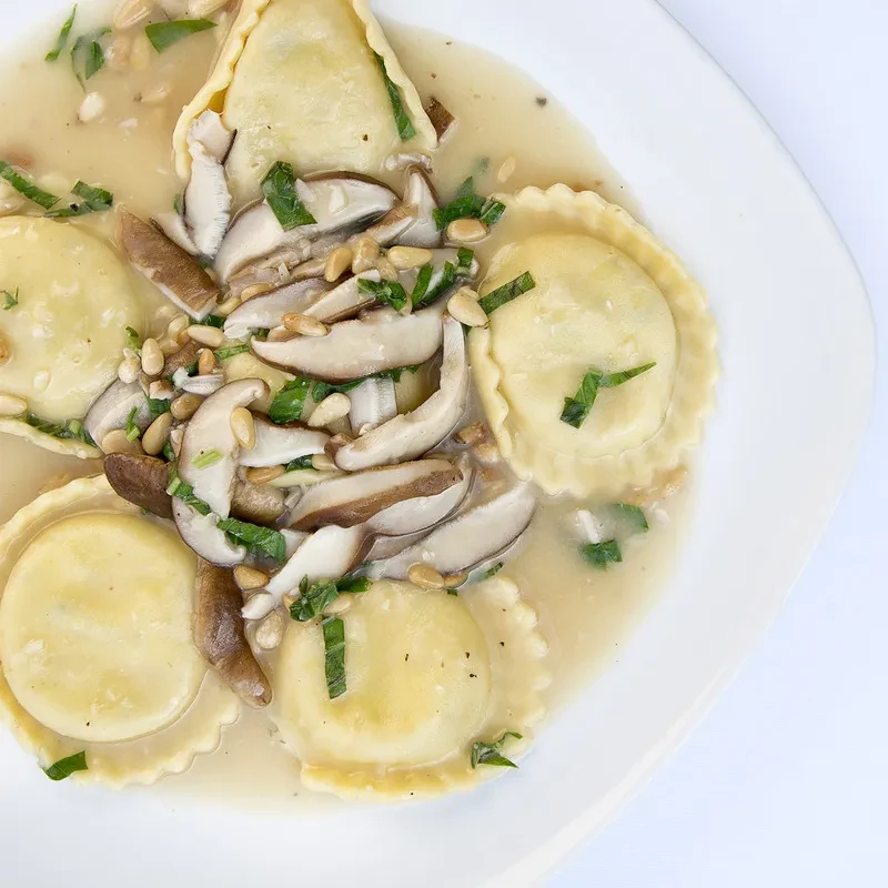 Ravioli in a creamy sauce with sliced mushrooms and pine nuts.