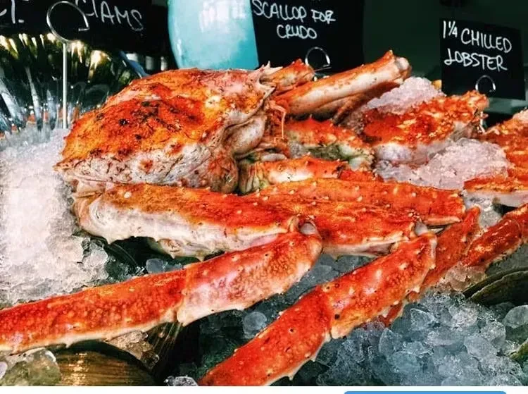 Fresh king crab legs and whole crab on ice display.