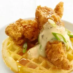 Golden fried chicken tenders, gravy, and green onions on a waffle.