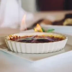 Creme brûlée in a white ramekin, with blue and yellow flames.