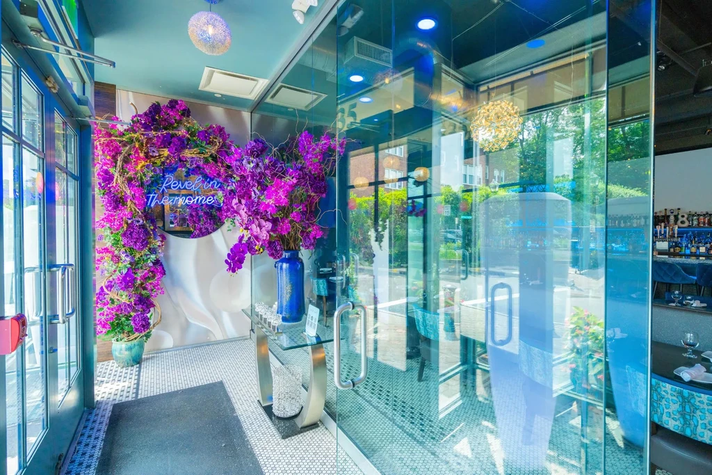 A restaurant entrance with purple floral decor and a neon sign.