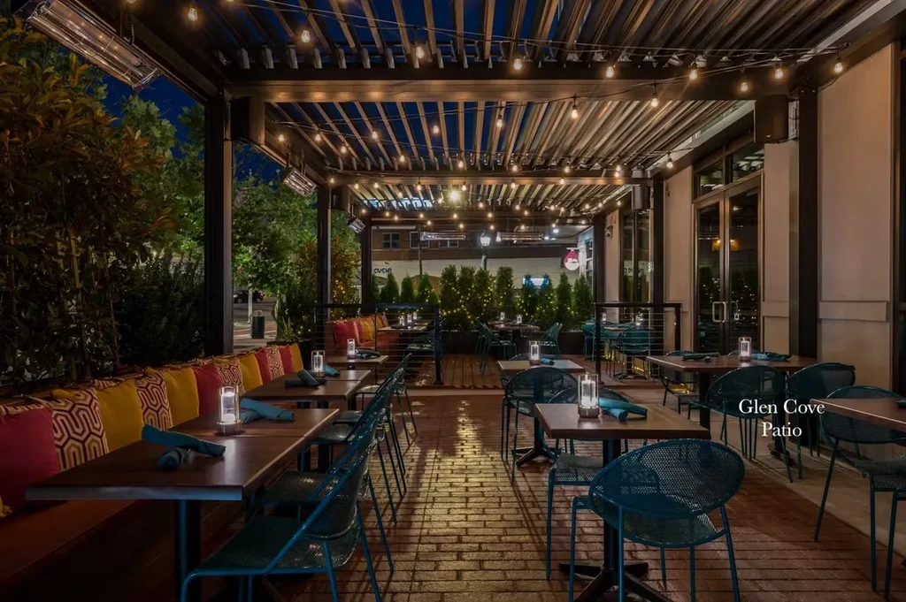A restaurant patio at night with string lights and colorful pillows.