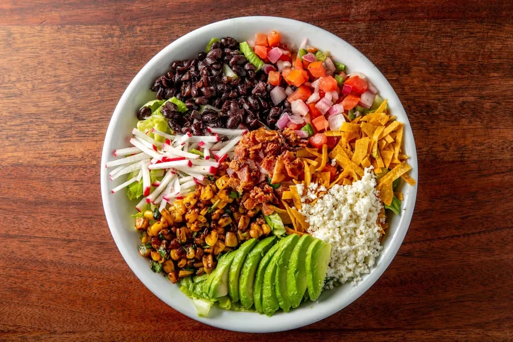 Overhead view of a large salad with many colorful toppings.