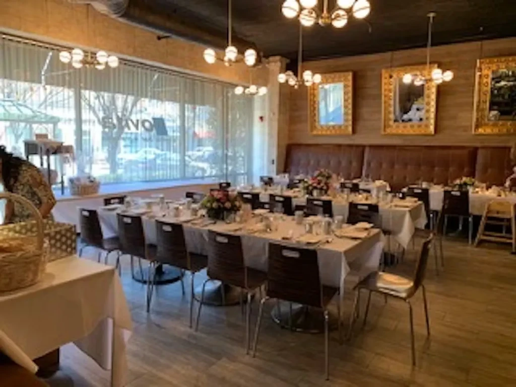 Restaurant dining room with tables set for an event, bathed in window light.