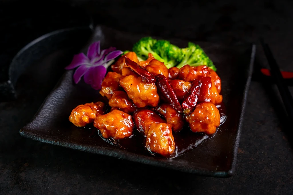 Kung Pao chicken with broccoli, red chilis, and purple flower.