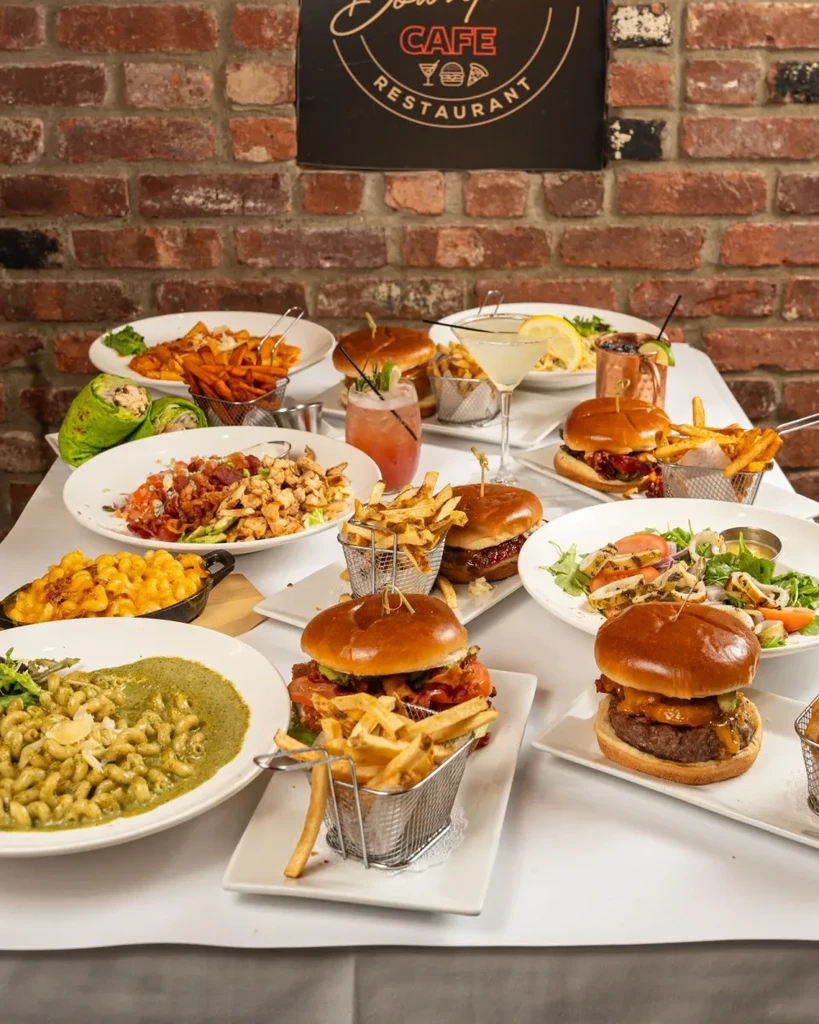 A table full of burgers, fries, pasta, salads, and cocktails.