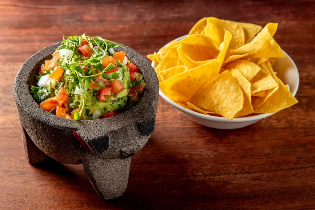 Guacamole in a molcajete and a bowl of tortilla chips.