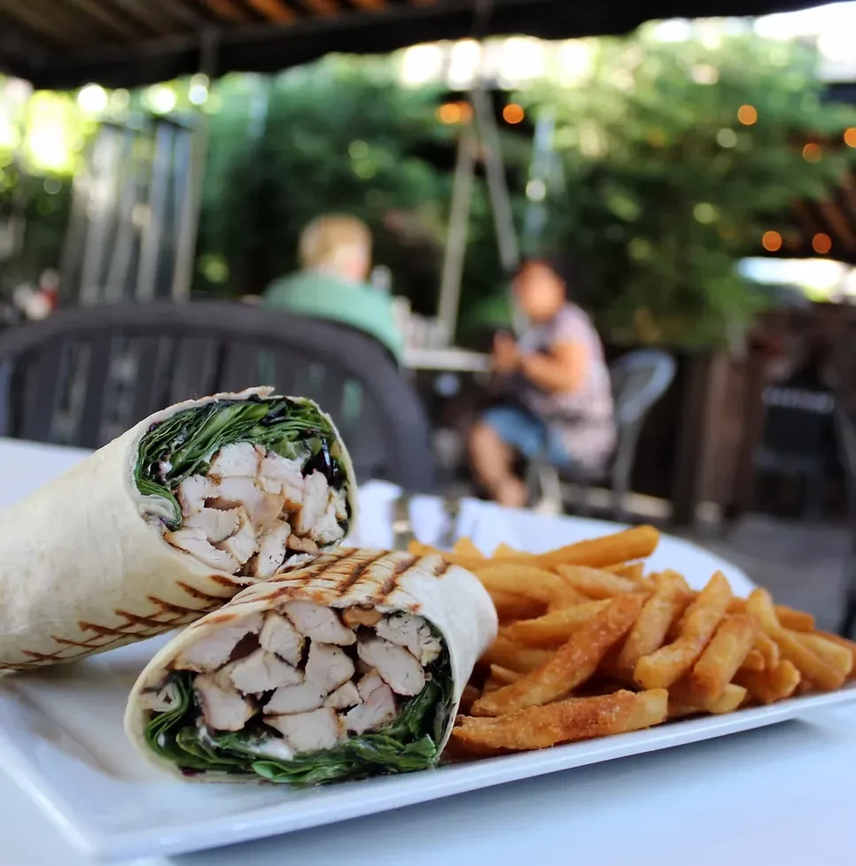 Two chicken wraps and a side of fries on an outdoor patio.